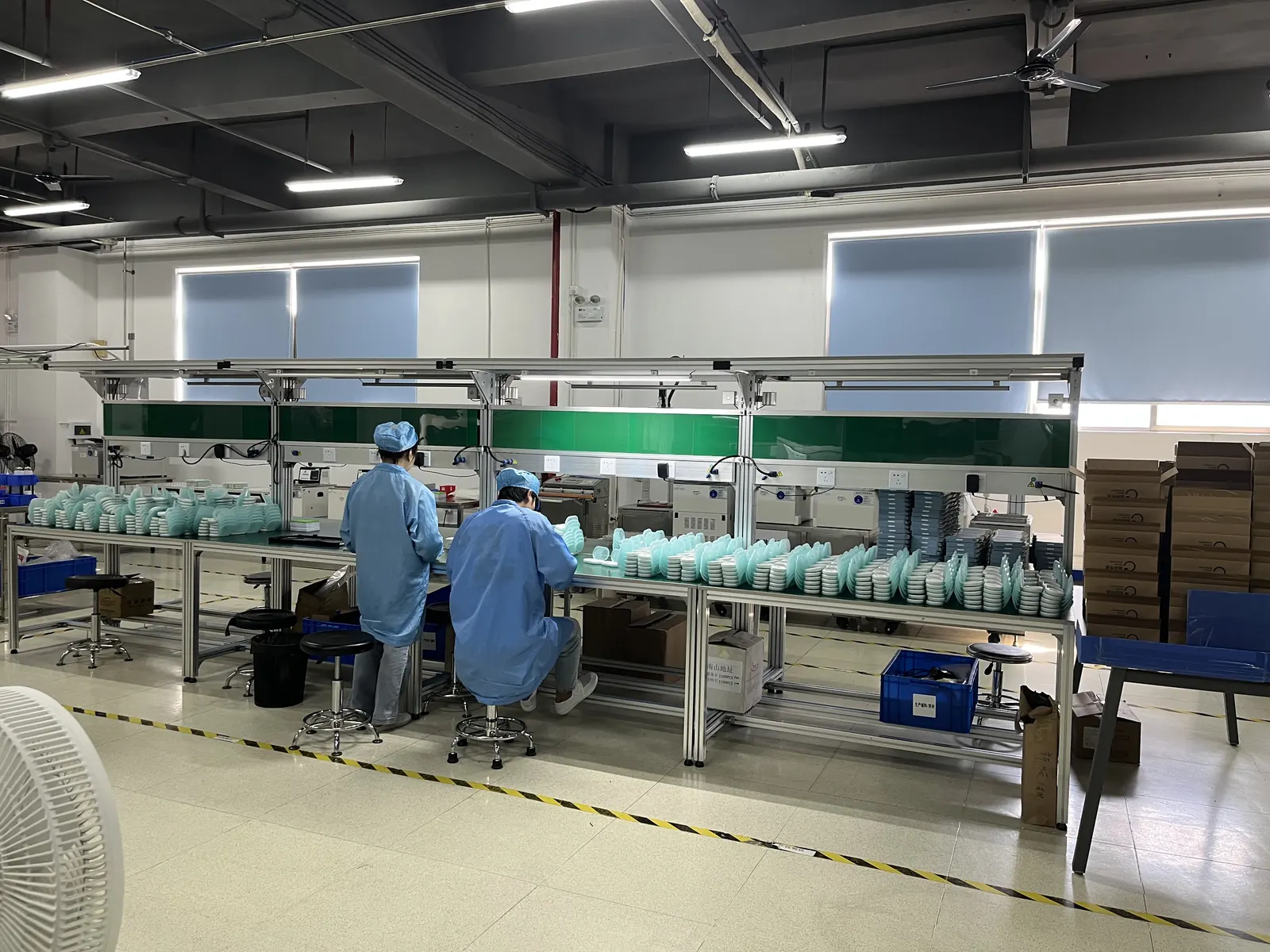 Thermometer assembly benches and packed cartons on the Longgang production floor