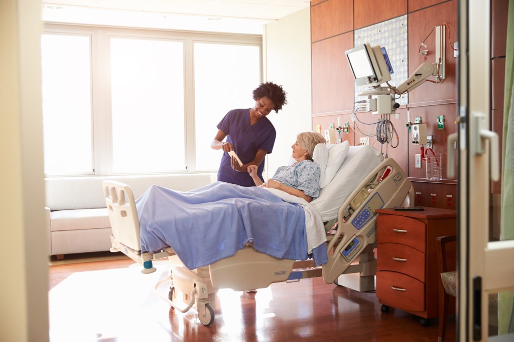 Caregiver attending to an elderly patient in a monitored room