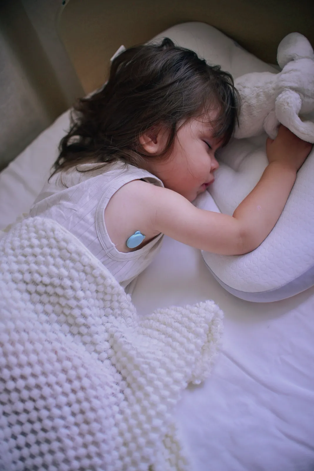 Child asleep at home wearing a P20 continuous temperature monitor on the upper arm