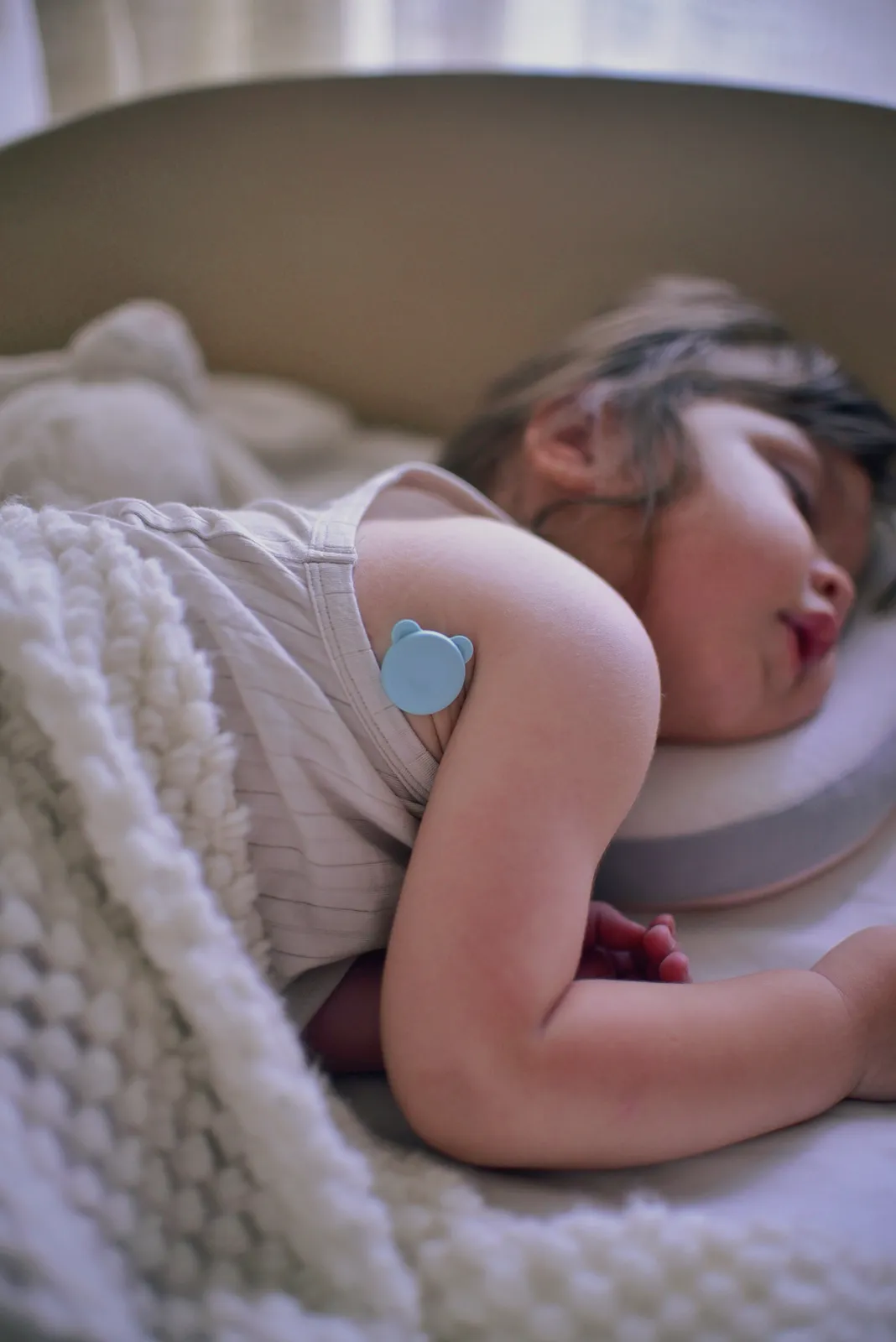 Close-up of the 2g P20 sensor attached under a sleeping child's arm with a hypoallergenic patch
